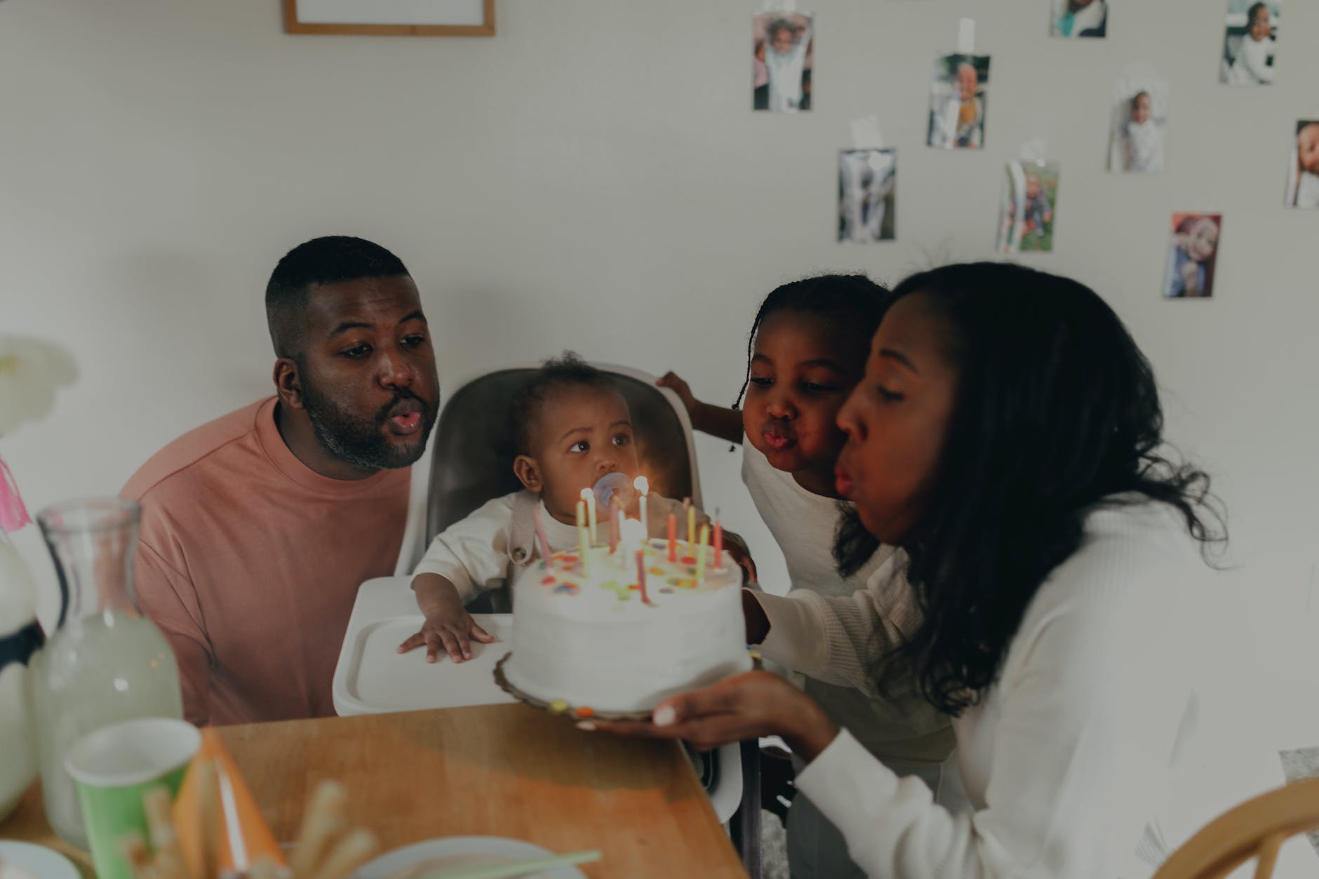 family with two children blowing out the candles on a birthday cake